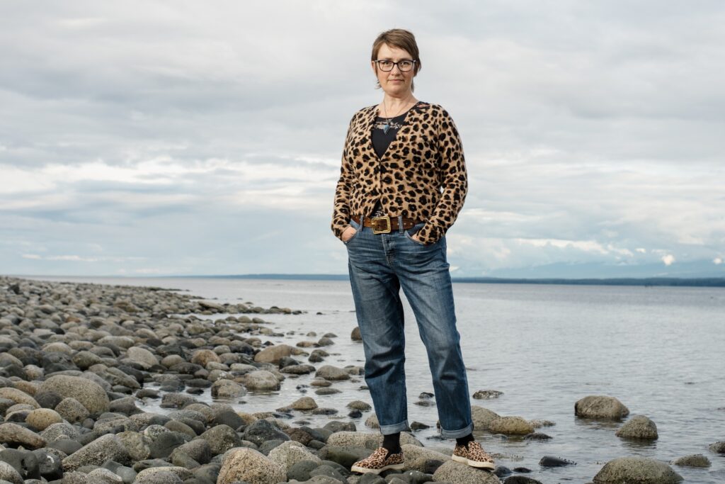 Robyn Mawhinney regional director for Area C, standing on a rocky beach.