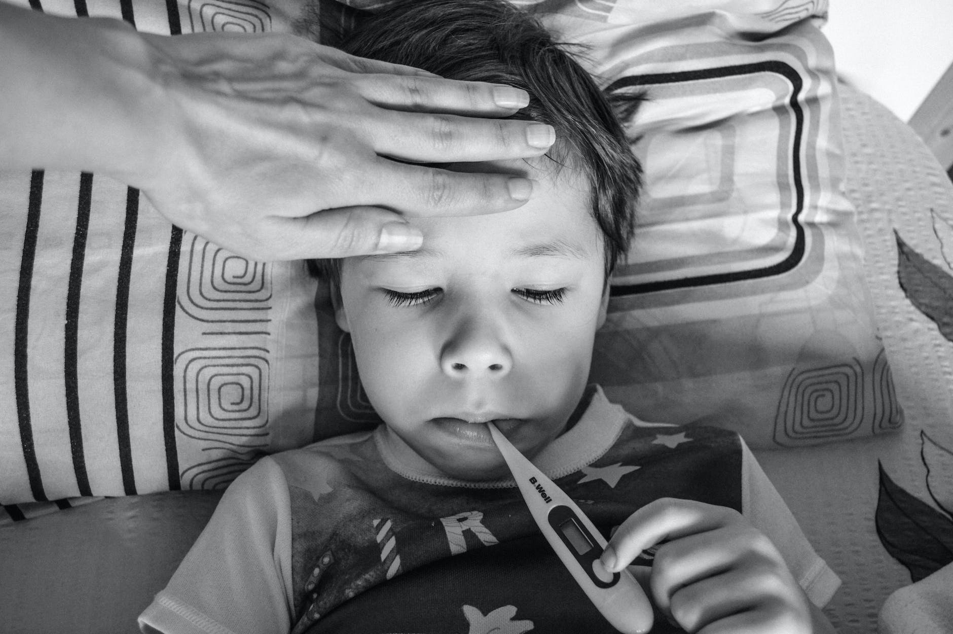 little boy keeping thermometer in mouth.