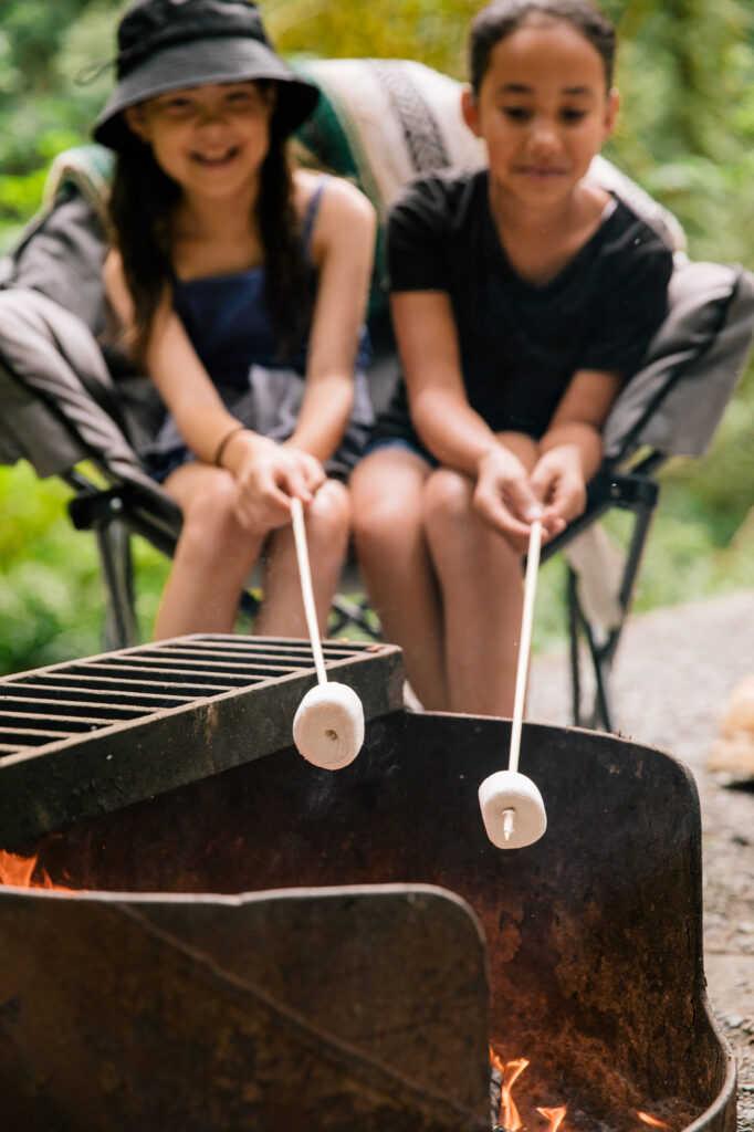 Two young girls roasting marshmallows over an open fire. 
