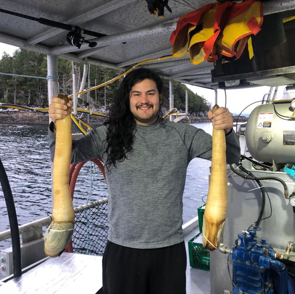 Lawson holding two Pacific Geoduck clams. 
