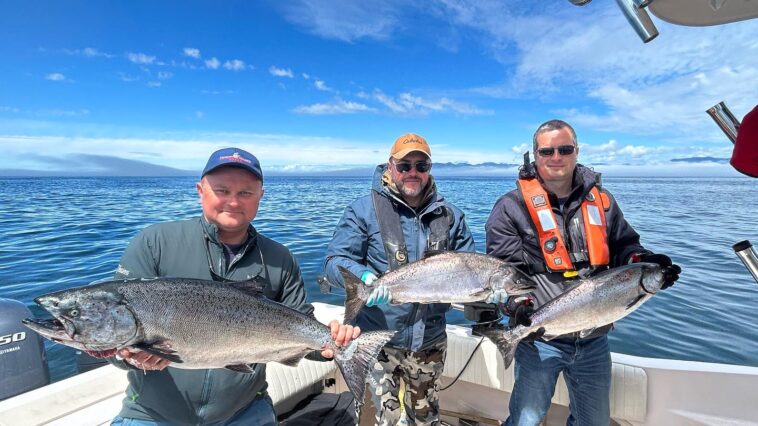 Sportfishers in Port Renfrew celebrate their successful day on the water, proudly displaying the magnificent Chinook salmon they reeled in.