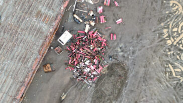 A pile of scrap metal next to a derelict barge at the Deep Water Recovery site.