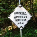 A road sign reading "mandatory watercraft inspection ahead"