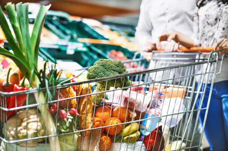 A couple shopping for groceries and pushing a trolley cart